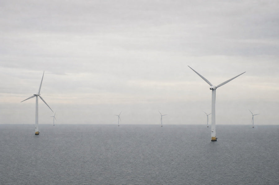 Vindmøller på havet en grå dag med fladt hav og tyndt, lyst skydække