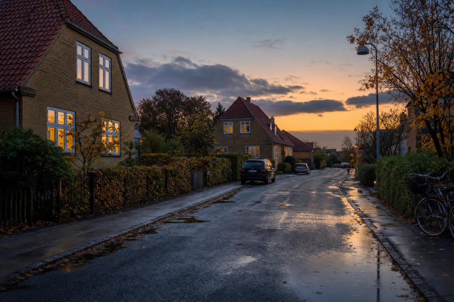 Stille dansk villavej i skumringen i efteråret med gule murstensvillaer, oplyste vinduer og våd asfalt. Illustration.